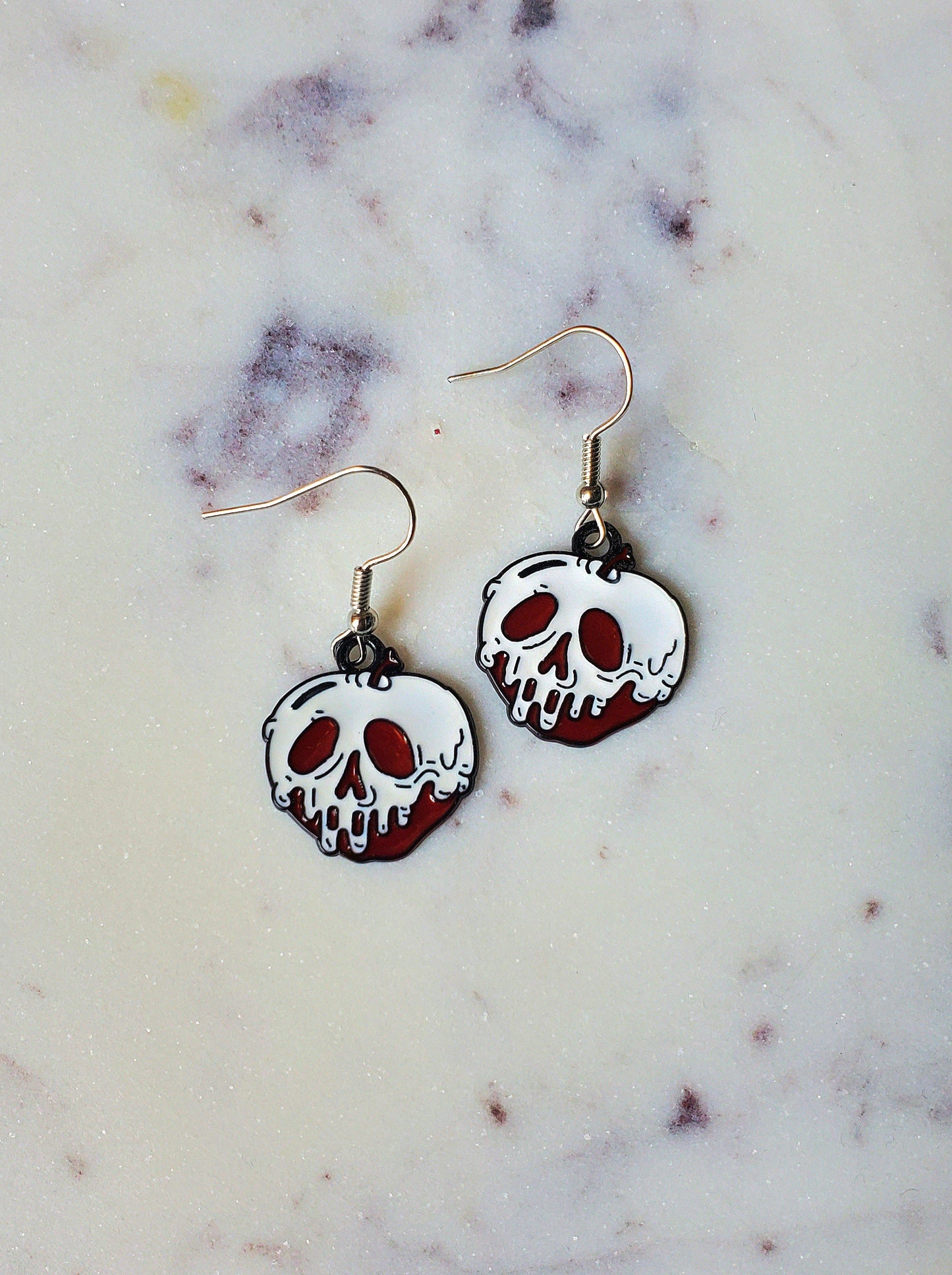Skull-shaped earrings on a marble surface