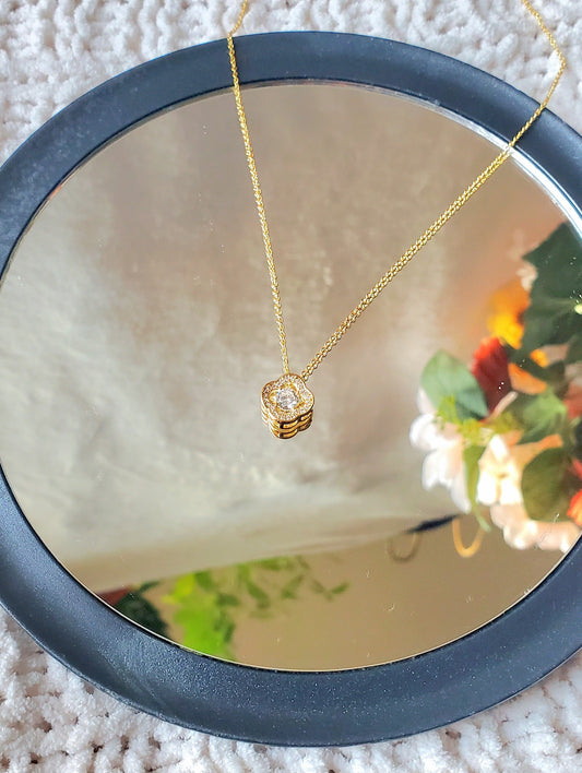 Gold necklace with a heart-shaped pendant on a textured surface