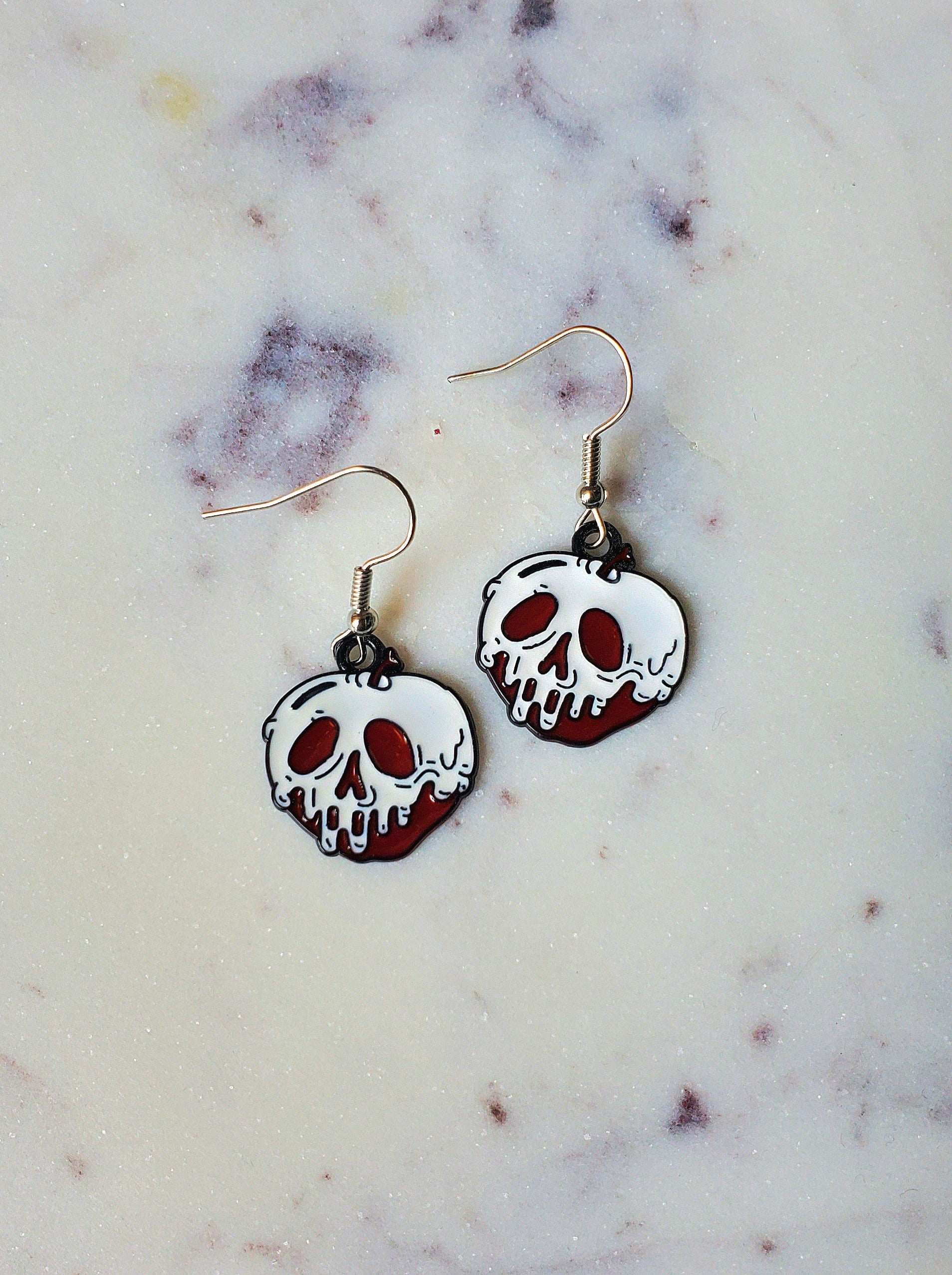 Skull-shaped earrings on a marble surface