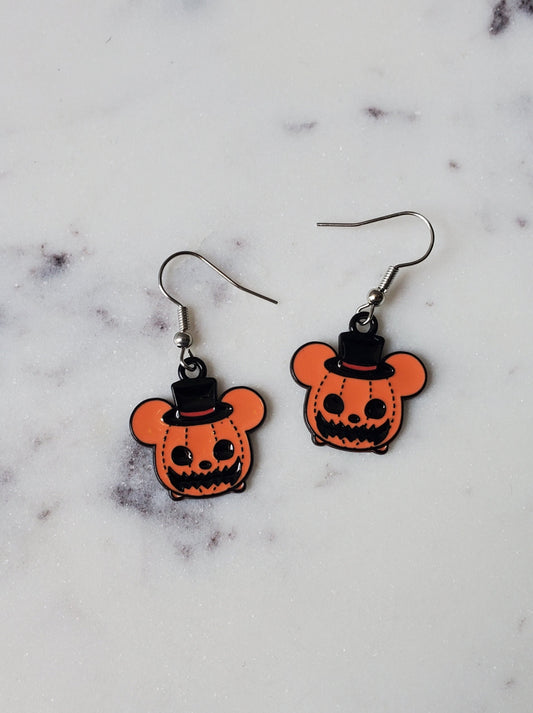 Pair of orange and black pumpkin-shaped earrings on a marble surface